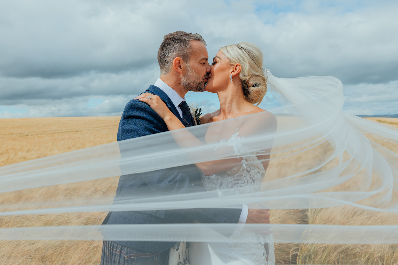 Bride and groom in field with veil overlay