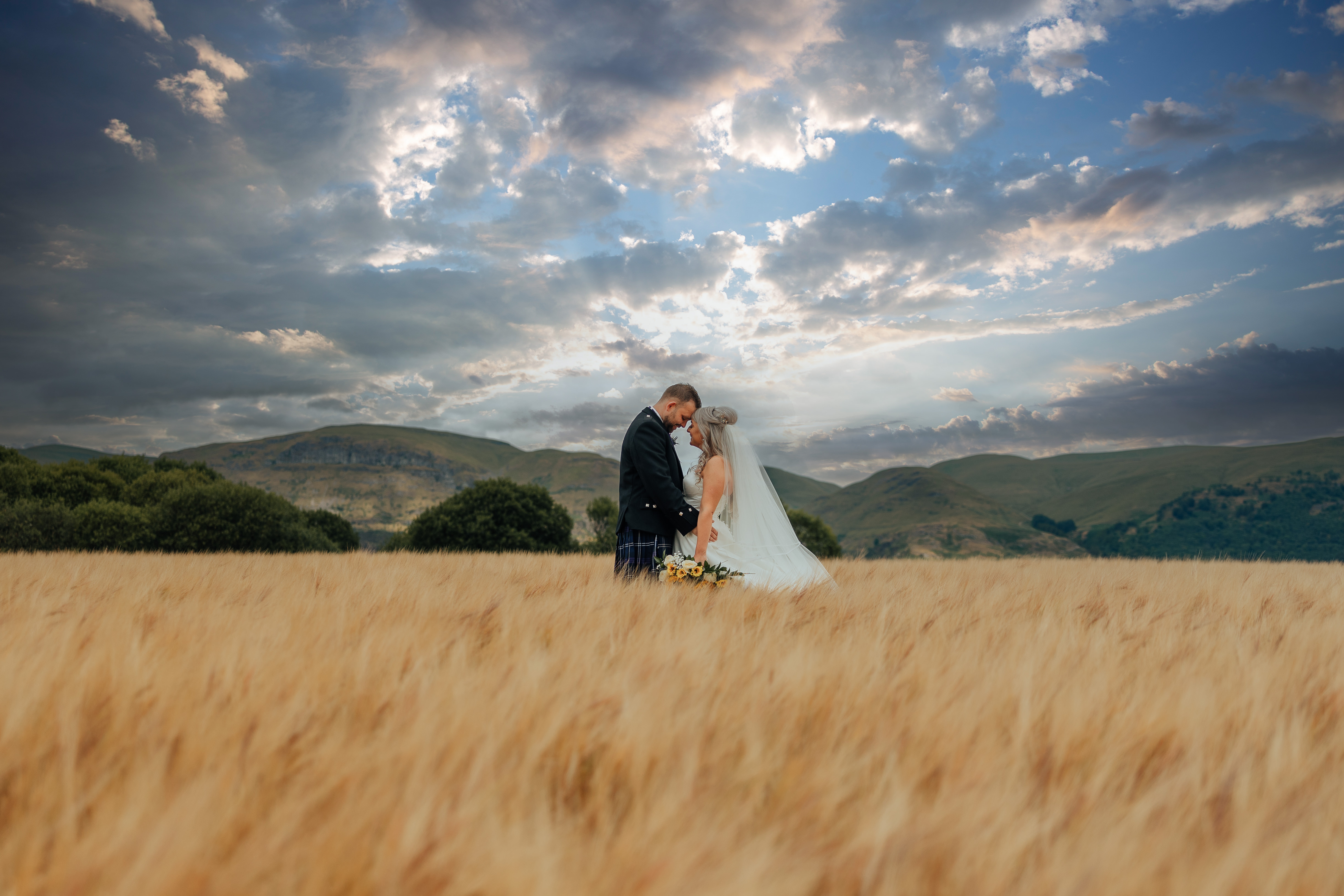 couple in field with dramatic sunset